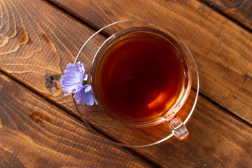 a glass mug with a chicory drink. A blue chicory flower floats in a cup with a drink