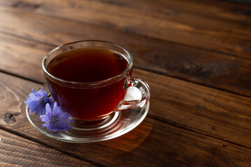 a glass mug with a chicory drink. A blue chicory flower floats in a cup with a drink