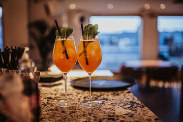A close up shot of two glasses of Aperol Spritz in a restaurant bar. Classic refreshing summer cocktails, ready to be served. Horizontail image.