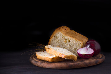 Freshly baked onion bread sliced into slices on a dark background