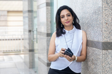 An Indian woman looking into her phone in an urban corporate setting