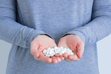 A handful of white pills on palms of a Caucasian woman close-up.