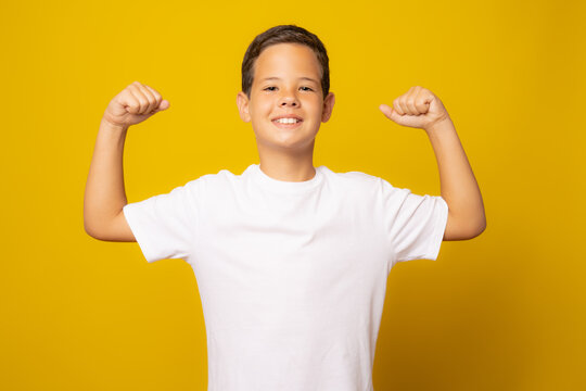 Strong Boy Showing Muscles, Isolated On Yellow Background