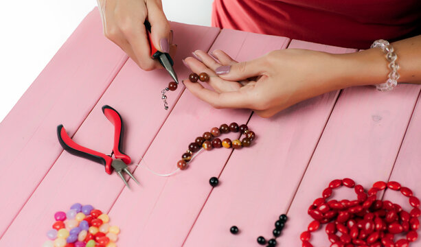 Jewelry making. Making a bracelet of colorful beads. The girl with the tools in the hands of manufactures bracelets.