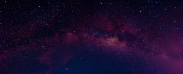 Milky way in the night sky and stars on dark background with noise and grain. Photo taken with long exposure and white balance selected.