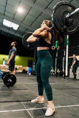 Fototapeta na wymiar Woman performing a weightlifting exercise inside a gym