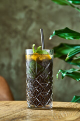 Alcoholic cocktail with gin and cola, lime and mint in a glass with ice