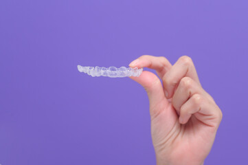 close up of woman's hand holding invisalign braces in studio, dental healthcare and Orthodontic...