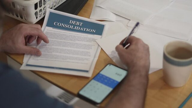 Man Calculating his Debt Consolidation Plan on Paper