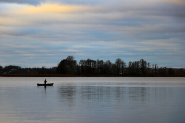 Obraz premium fisherman in a boat on the lake in the fall.