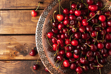 a lot of ripe cherries are lying on a copper tray with a pattern.