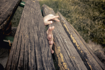 Children's hands between old wooden planks. The child's hands are stuck between the wooden planks