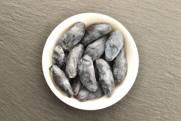 Several organic ripe honeysuckle berries on a white saucer on a stone, close-up, top view.