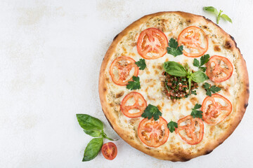 Pizza with chicken and garlic, Caesar sauce, pork, tomatoes and Mozzarella cheese on a light background.