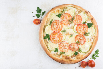 Pizza with chicken and zucchini, Caesar sauce, tomatoes, Parmesan cheese and Mozzarella on a light background.