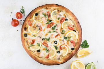 Pizza with salmon, Caesar sauce, tomatoes, Parmesan cheese and Mozzarella, olives and lemon on a...