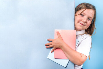 Naklejka premium Back to school concept. School invitation, advertisement banner. Cute primary school student girl in white blue classic uniform, with books, notepads. Colorful bright blue background copy space