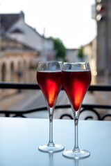 Drinking of Kir Royal,  French aperitif cocktail made  from creme de cassis topped with champagne, typically served in flute glass, with view on old French village