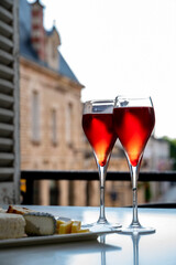 Drinking of Kir Royal,  French aperitif cocktail made  from creme de cassis topped with champagne, typically served in flute glass, with view on old French village
