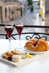 Drinking of Kir Royal,  French aperitif cocktail made  from creme de cassis topped with champagne, typically served in flute glass, with view on old French village