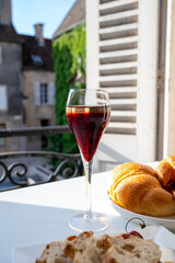 Naklejka premium Drinking of Kir Royal, French aperitif cocktail made from creme de cassis topped with champagne, typically served in flute glass, with view on old French village