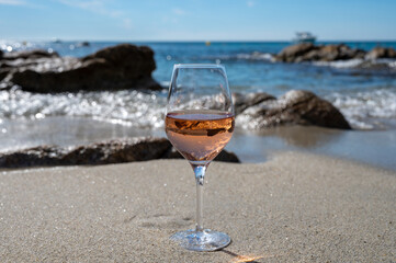 Summer time in Provence, glass of cold rose wine on sandy beach and blue sea near Saint-Tropez, Var department, France