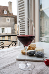 Tasting of burgundy red wine from grand cru pinot noir  vineyards with french goat cheeses and view on old town street in Burgundy wine region, France
