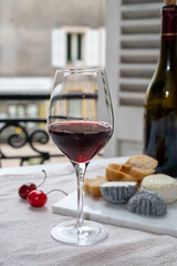 Tasting of burgundy red wine from grand cru pinot noir  vineyards with french goat cheeses and view on old town street in Burgundy wine region, France
