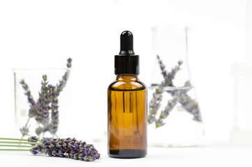 Lavender essential oil in a brown bottle with a dropper. Natural essential oil and lavender flowers on white background