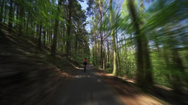 A rear view of the female cyclist riding a bicycle in the Divoka Sarka nature reserve in Pague.
