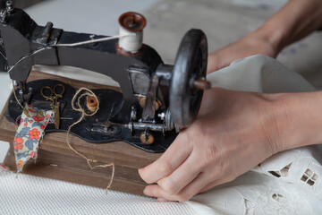 Manual sewing machine stands on white fabric