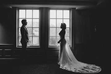 bi racial couple standing apart in front of window shot in black and white - Powered by Adobe