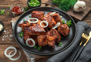 Fried meat with herbs and onions close-up on a wooden background.