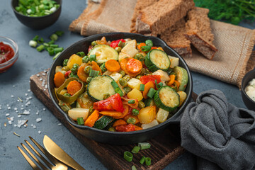 Frying pan with baked vegetables on a gray-blue background.