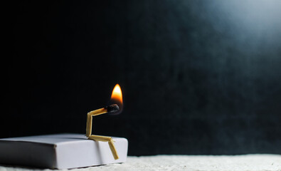 Concept of weakness, sadness, and loneliness. Image of a man-made matchstick. Burning matchstick man sitting alone without a partner. Matchstick art photography.