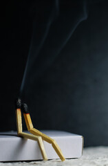 Two matches burning sitting together on the matchbox in the dark copy space. Two matches in flame...