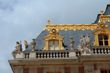 Roof of Versailles palace in France decorated with gold and antique style statues of beautiful women, a famous French tourist destination near Paris.