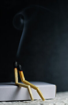 Two matches burning sitting together on the matchbox in the dark copy space. Two matches in flame as a metaphor of togetherness friendship, Love And Romance Concept. Matchstick art photography.