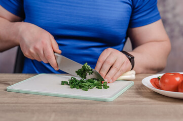 A man cuts green onions on a board. Healthy eating