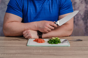 A man cuts green onions on a board. Healthy eating
