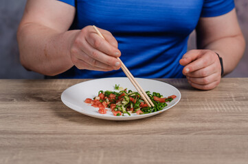 Salad with cucumber, tomato and green onions on a plate. A man holding a plate of salad