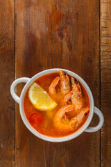 Tom yam soup with shrimps and coconut milk on a wooden table.