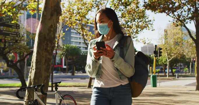 Asian woman wearing face mask using smartphone standing in the park
