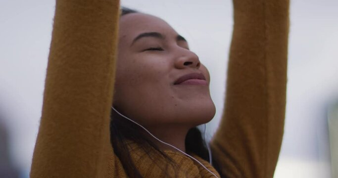 Asian woman wearing earphones listening to music and smiling
