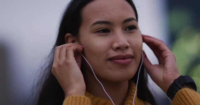 Asian woman wearing earphones listening to music and smiling