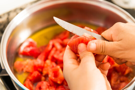 Detail of a woman's hands by cutting tomatoes with a knife.