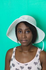 Young African American woman with vintage pink dress, hat and green background, in the city of Cali Valle del Cauca Colombia.