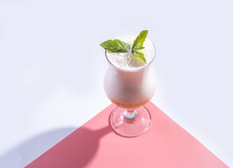 a cold cocktail of fruit juice and Indian drink lassi with mint on a pink background. top view