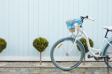 Fototapeta na wymiar Cute white bike with busket on blue wall. South side near sea.
