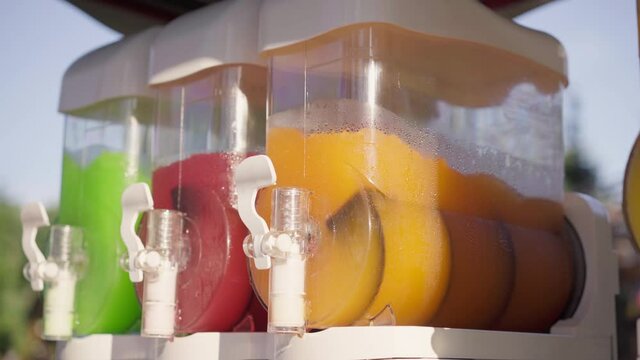 Machine Making Ice Slushy Drinks Outdoor Park Summer Red Orange Green Color. Iced Juice Mixer Machine Juicer Containing Smoothie Cocktail High quality 4k footage